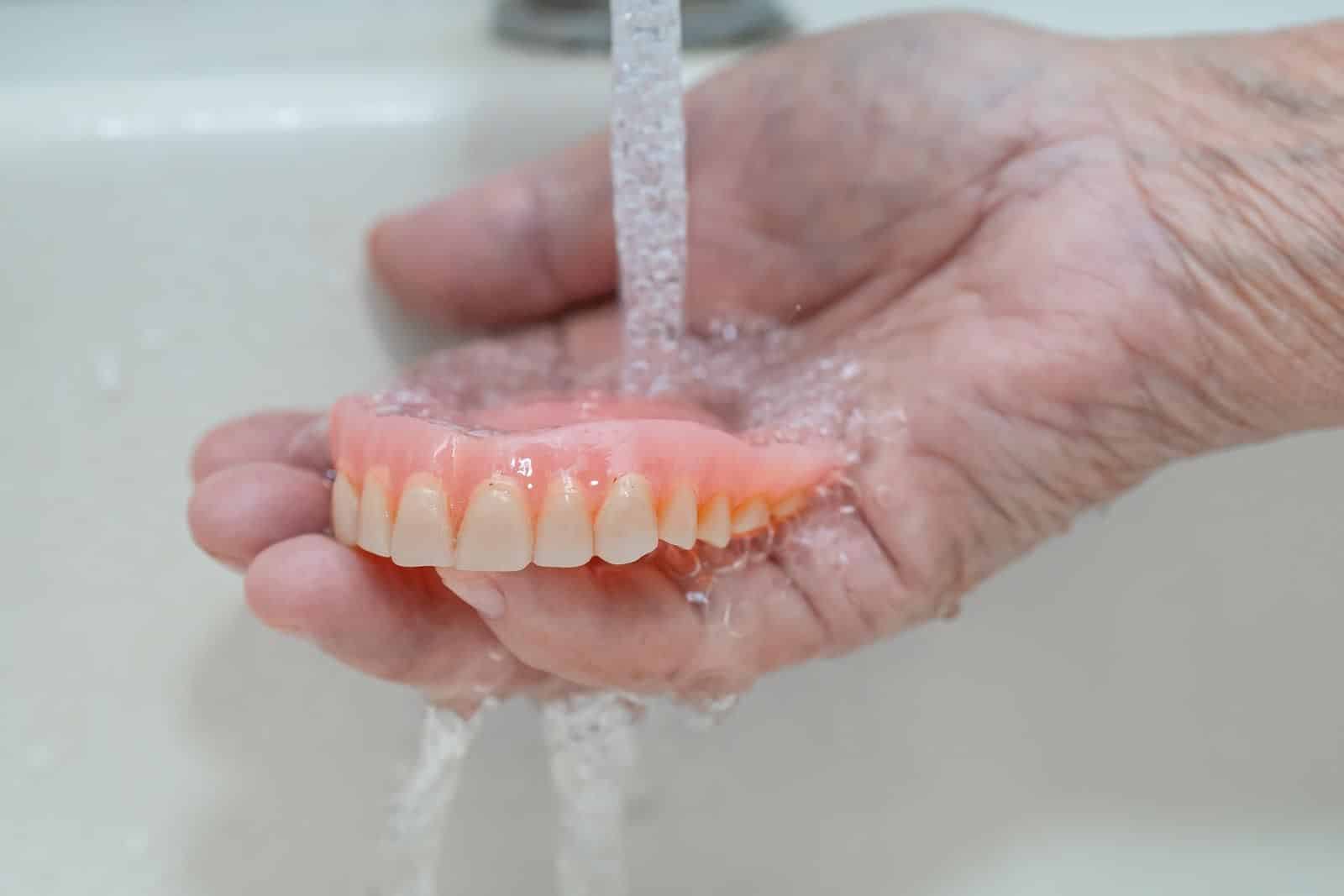 Person rinsing their dentures